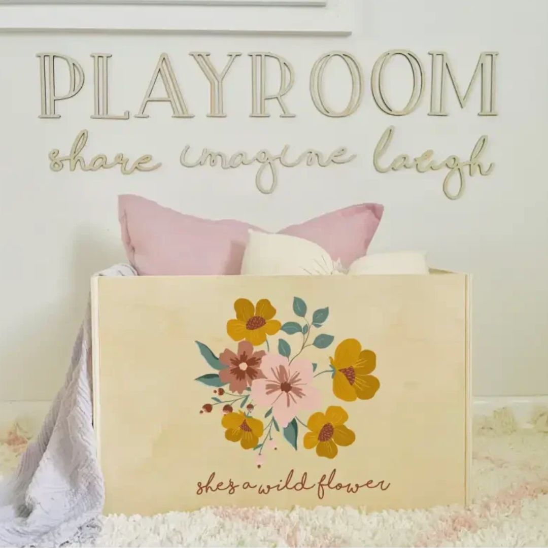 Personalised Wooden Toy Box with flower design and custom phrase in a child’s playroom.