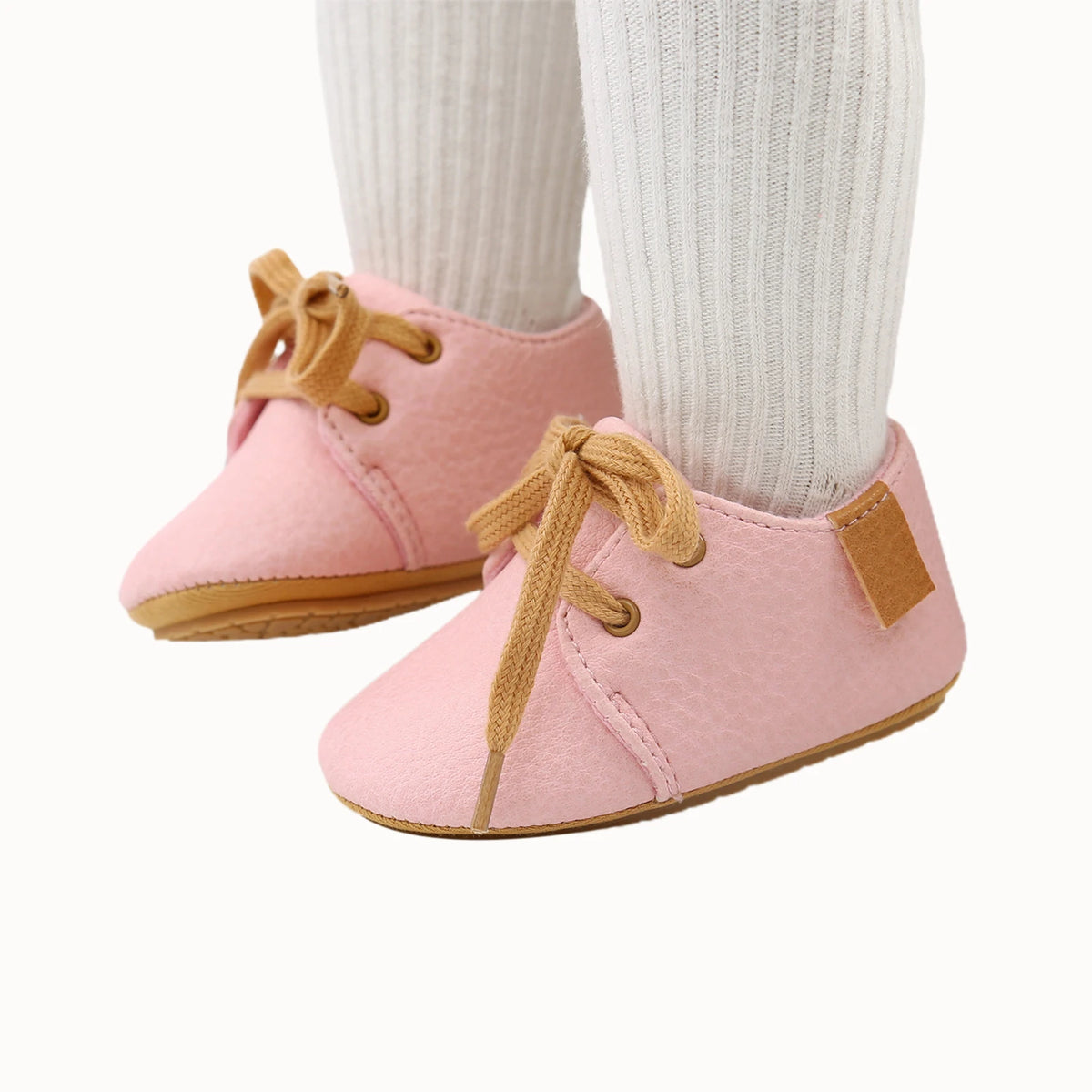 Styled photo of pink oxford style baby shoes worn with white socks