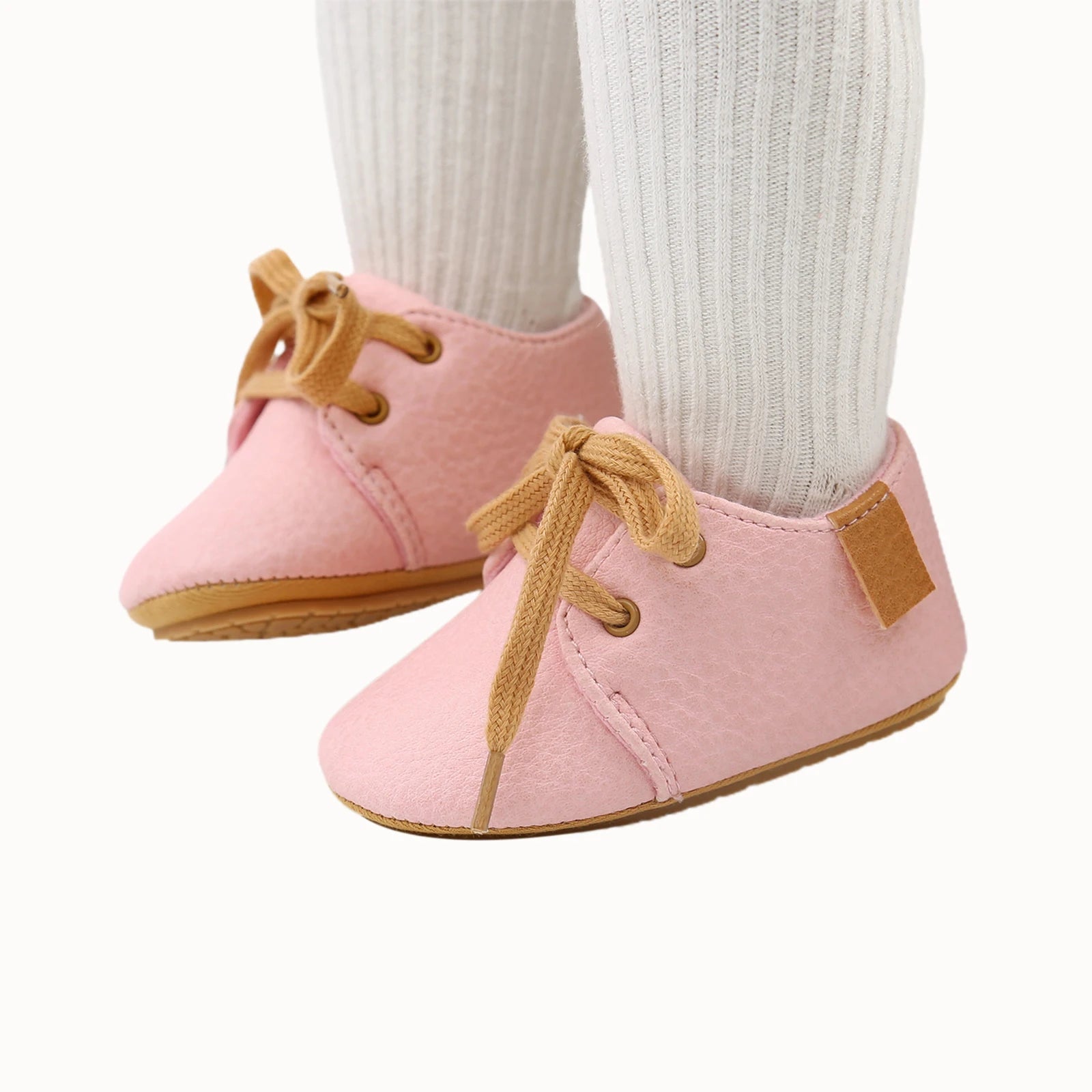 Styled photo of pink oxford style baby shoes worn with white socks
