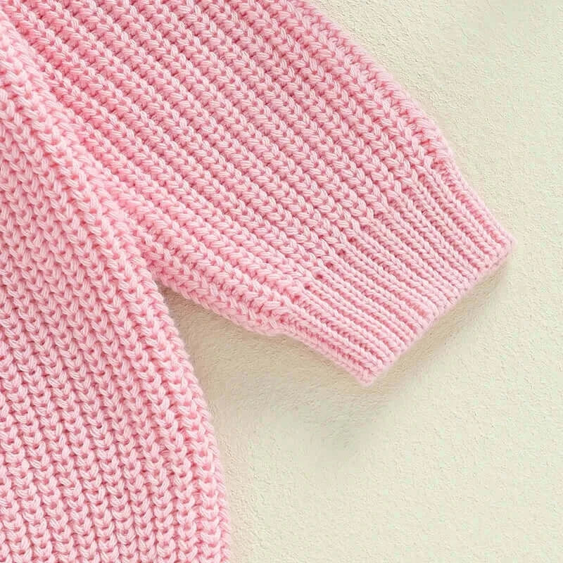 Close-up of the knitted sleeve of the Matching Sister Pink Jumper, showcasing its soft pink fabric and ribbed cuffs.