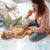 A mother changing a baby's diaper using a Plush Nappy Caddy for organised baby essentials on a bed.