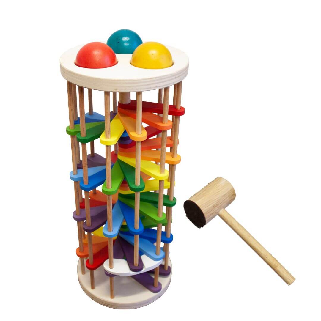 Toddler playing with wooden pound a ball tower with rainbow coloured curved tracks, three balls and wooden hammer
