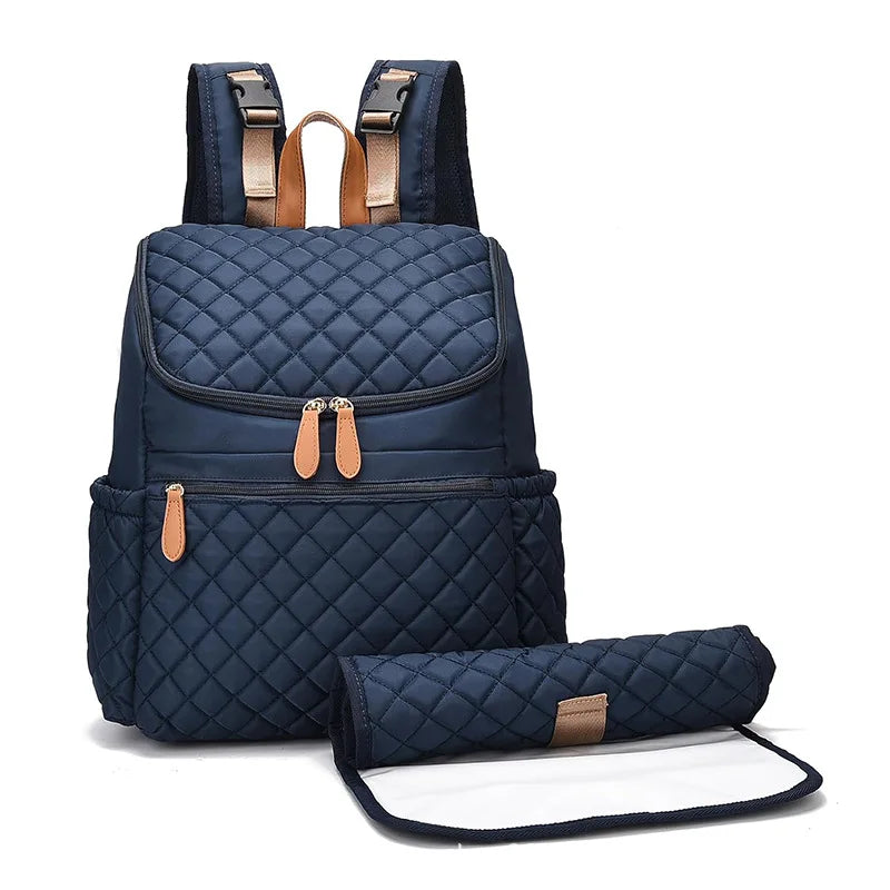 Navy blue quilted nappy backpack with change mat, perfect baby bag for stylish parents on the go.
