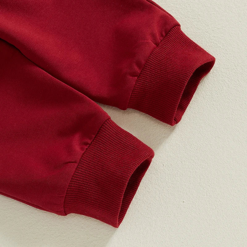 Close-up of red trackie pants cuffs from a baby Christmas outfit, featuring soft fabric and elasticated waist.