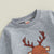 Close-up of grey pullover top with a reindeer graphic, part of a baby Christmas outfit for festive celebrations.