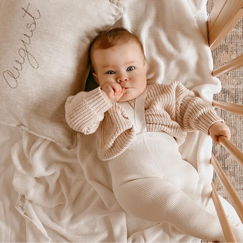 Baby boy wearing ribbed white suspender tights with knit jumper