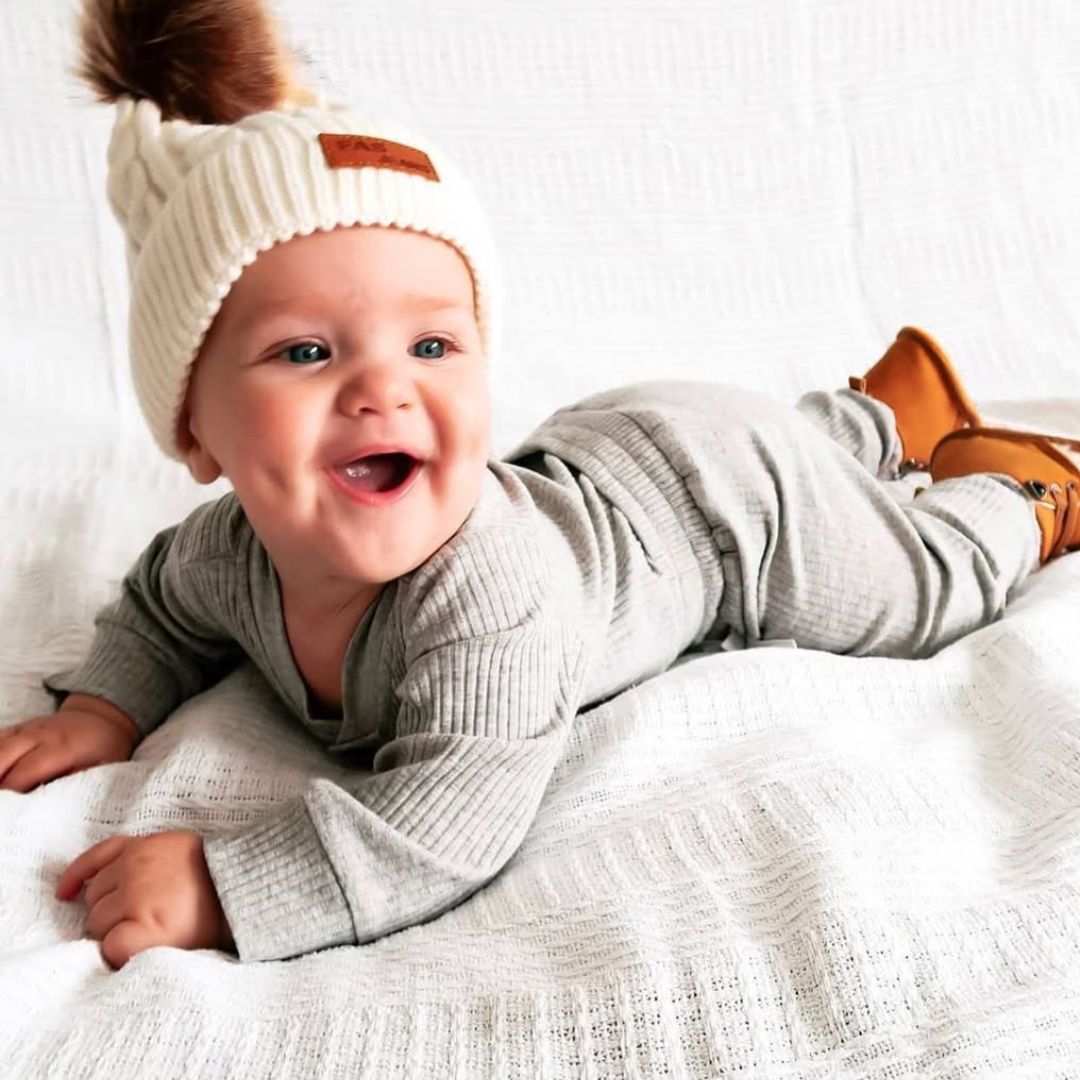 Smiling baby boy wearing ribbed bodysuit and pants set from Lulu Babe, in grey
