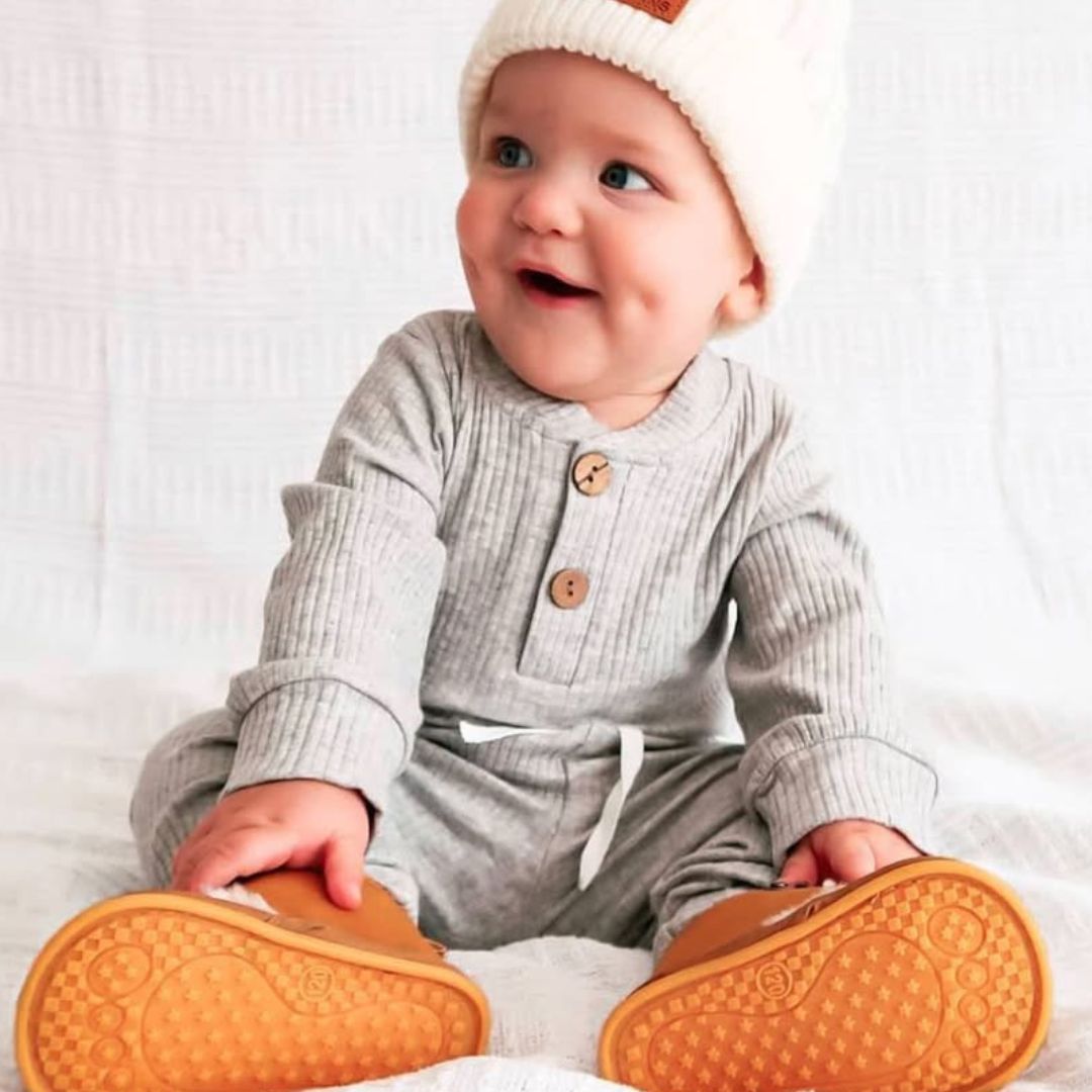 Smiling baby boy wearing comfy ribbed bodysuit and pants set from Lulu Babe, in grey
