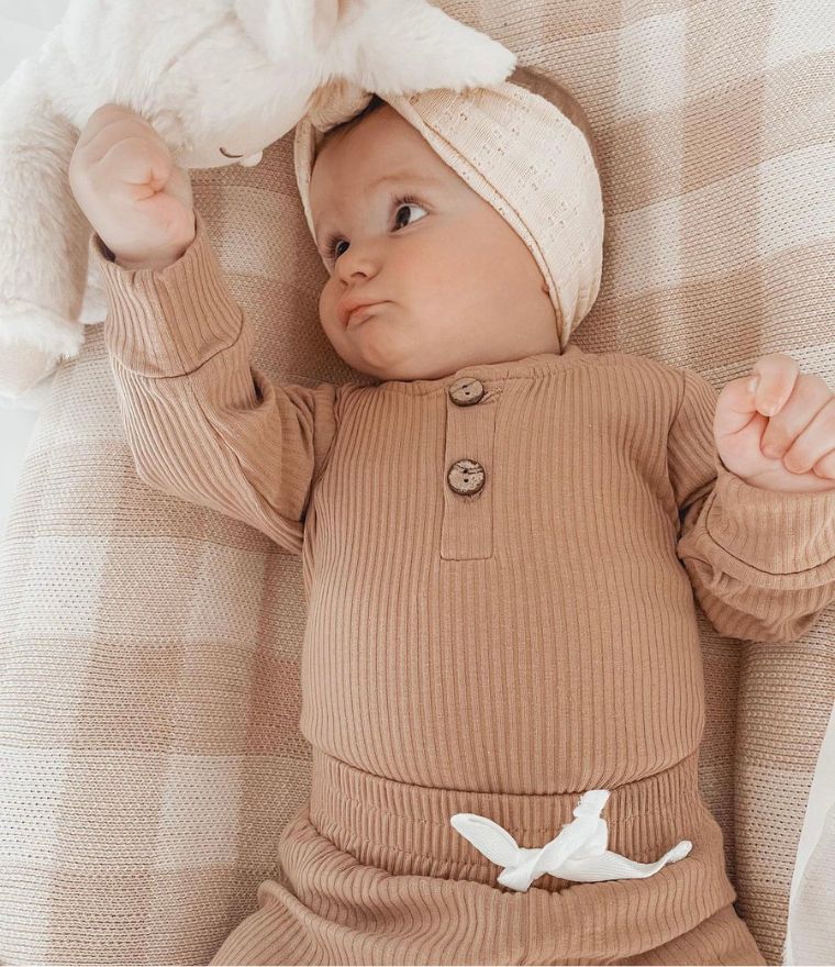 Baby girl wearing ribbed long sleeve bodysuit and pants set in latte, from Lulu Babe