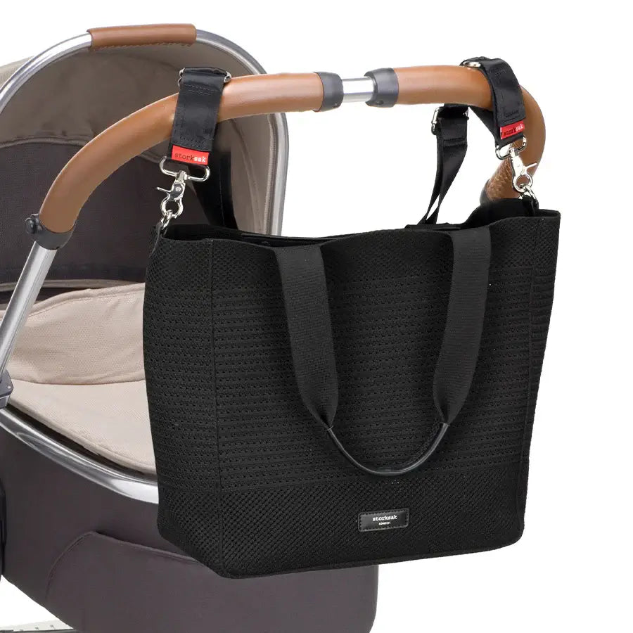 Storksak Thea Tote bag in black, stylishly attached to a stroller for modern parents' convenience.