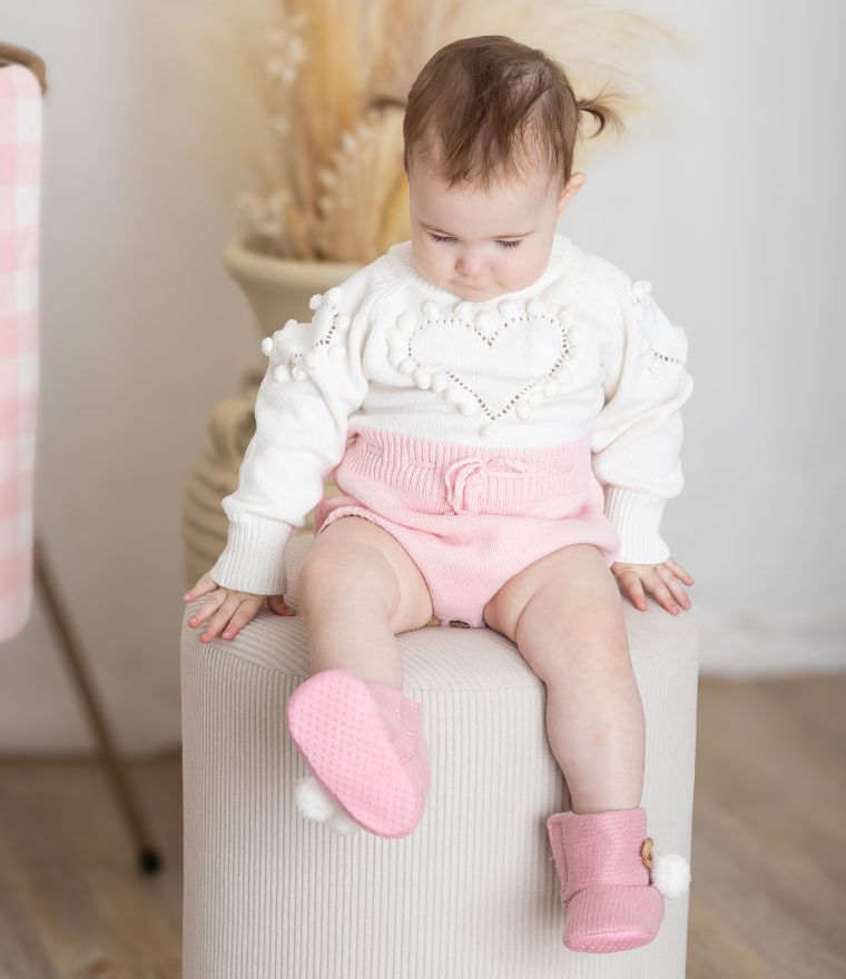 Baby girl wearing knit heart winter romper in pink
