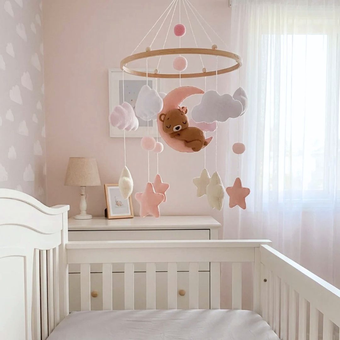 Baby cot mobile with plush teddy and stars hanging over a cot in a nursery