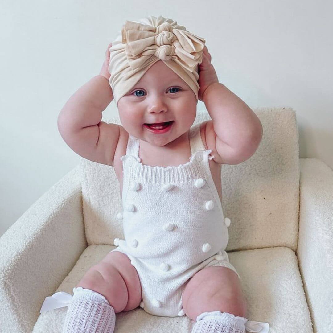 Baby girl wearing our Lexi Romper in white and Triple Knot Baby Turban