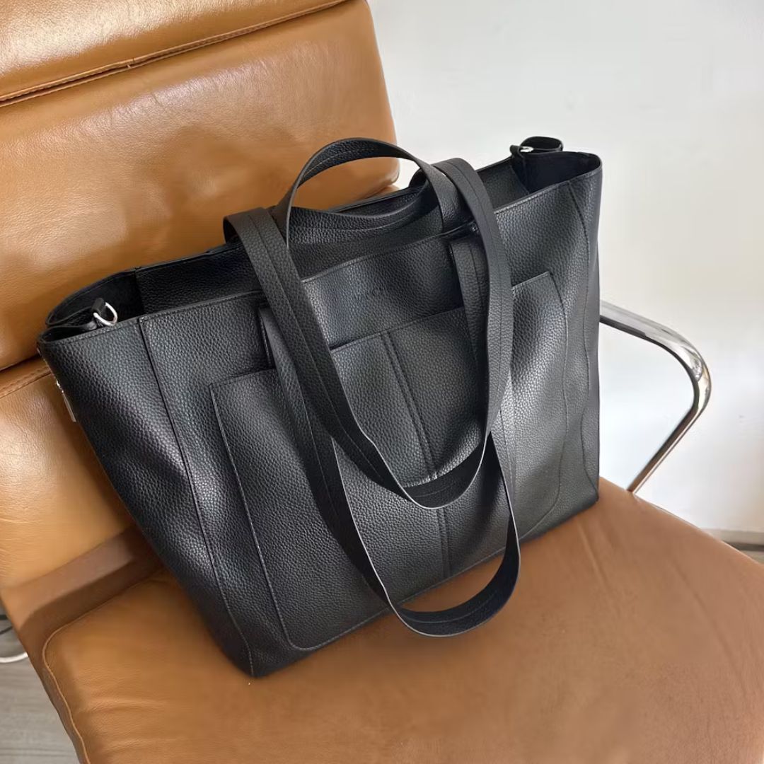 VANCHI Ida Nappy Tote Bag in black sitting on a leather chair