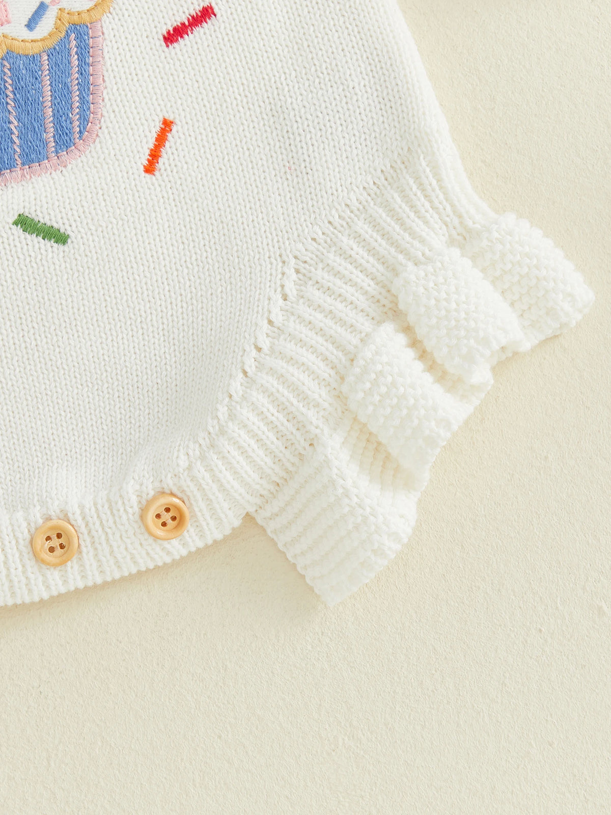 Closeup of baby girl first birthday romper in white showing ruffle hem