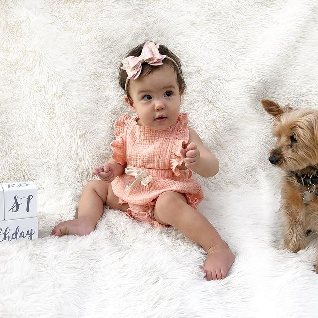 Baby girl wearing pink ruffle baby romper in milestone photo