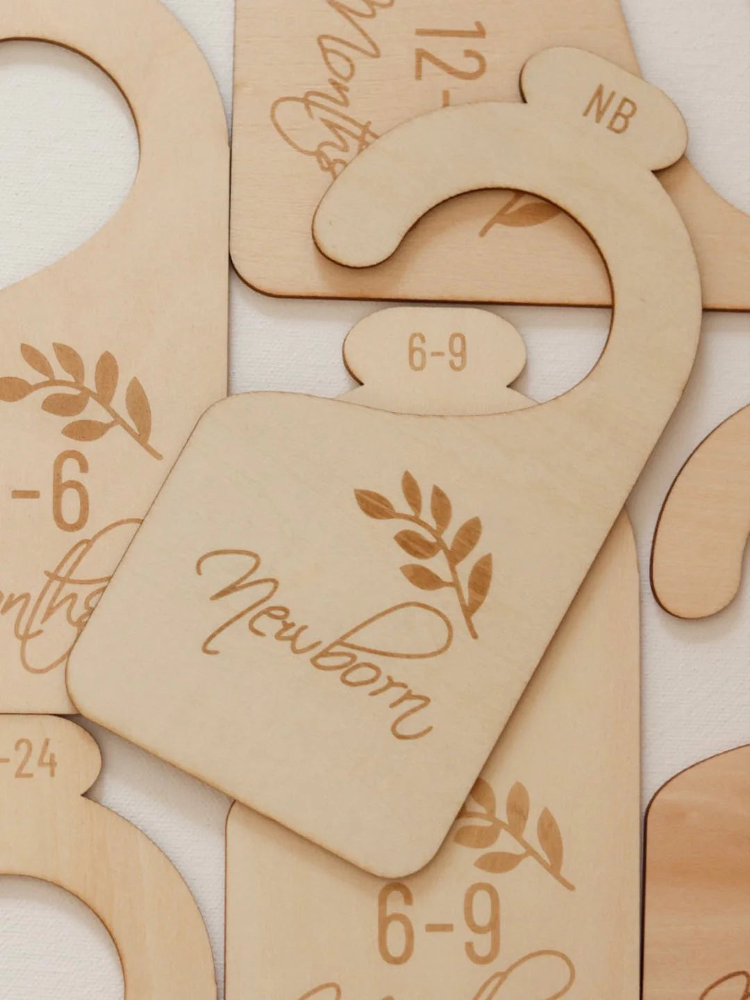 Seven laser-engraved wooden baby wardrobe dividers with botanical fern motif