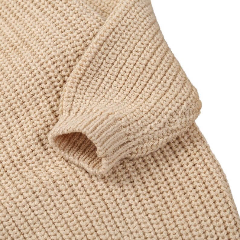 Closeup of baby knitted jumper in beige, showing the knit fabric