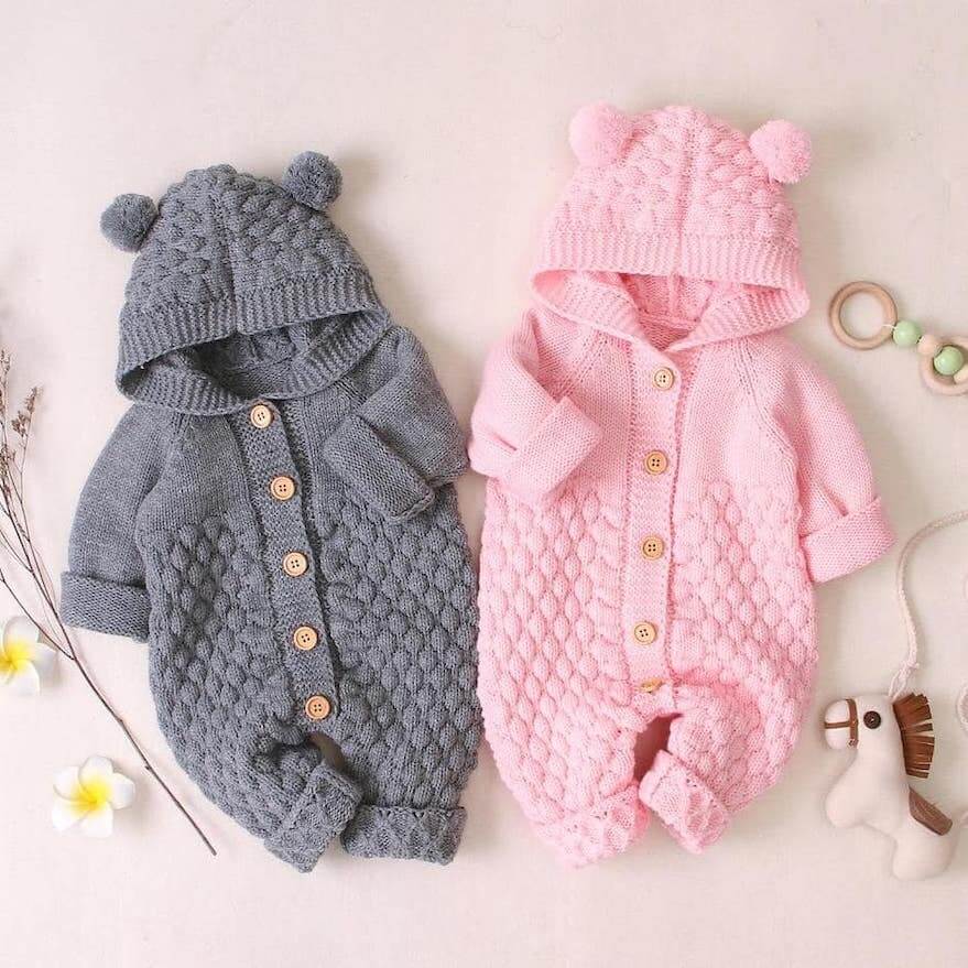 Flatlay of our knitted baby bear onesies in grey and pink