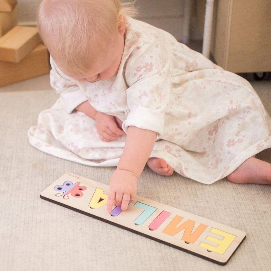 Baby girl playing with her custom-made name puzzle from Lulu Babe