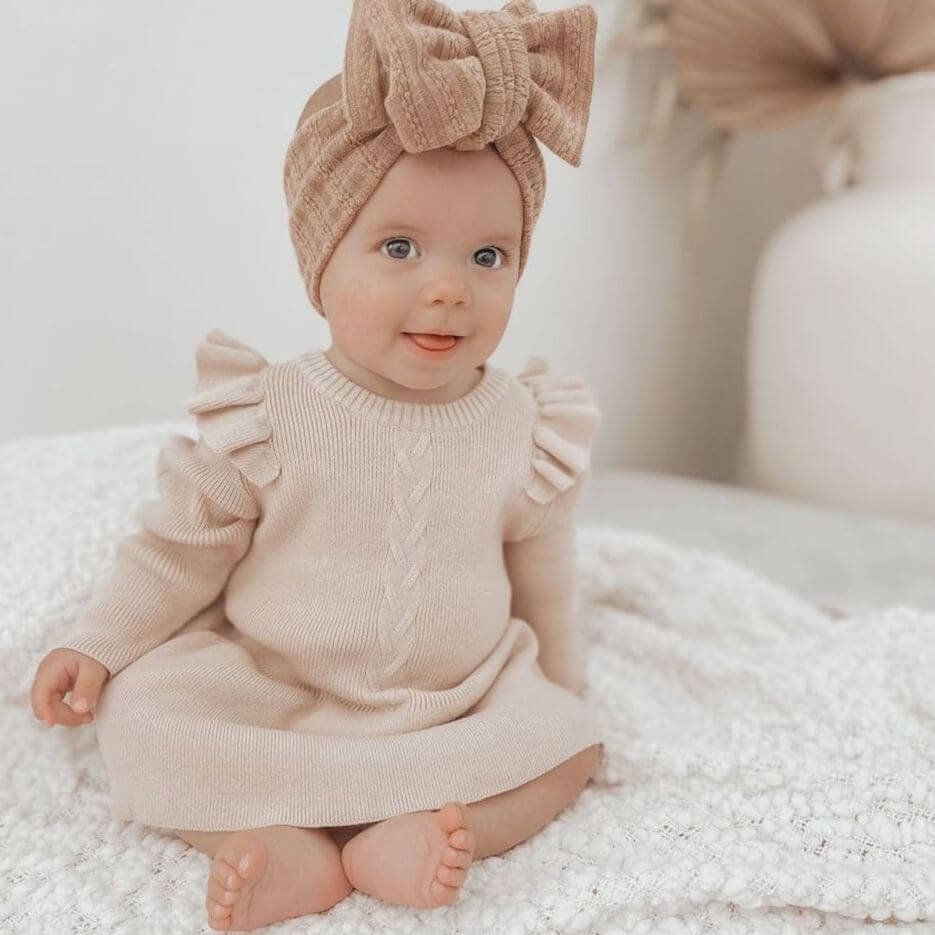 Baby girl wearing Poppy Winter Knit Dress in oatmeal from Lulu Babe