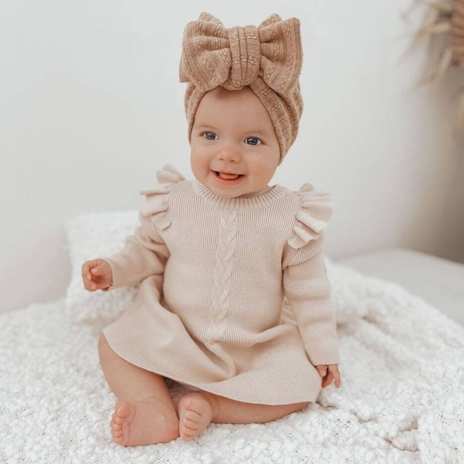 Baby girl wearing Poppy Winter Knit Dress in oatmeal from Lulu Babe