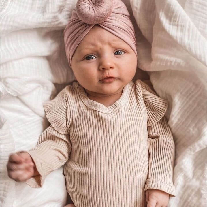 Baby girl wearing our ribbed Flutter Baby Romper in beige